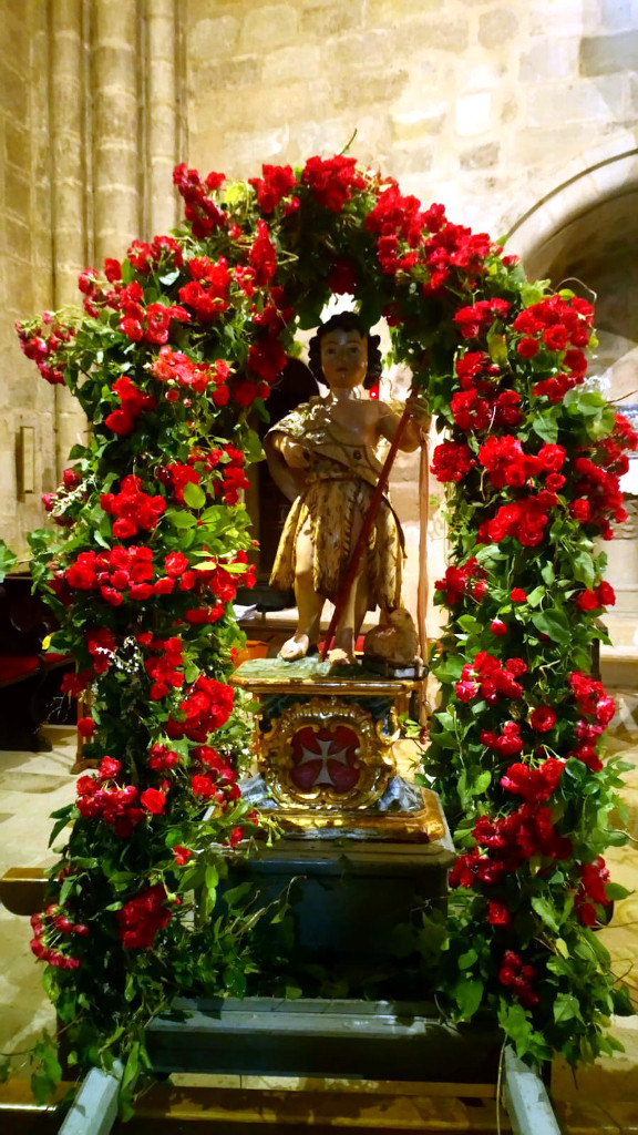 La imagen del santo en sus andas, engalanadas con arcos decorados con rosas rojas